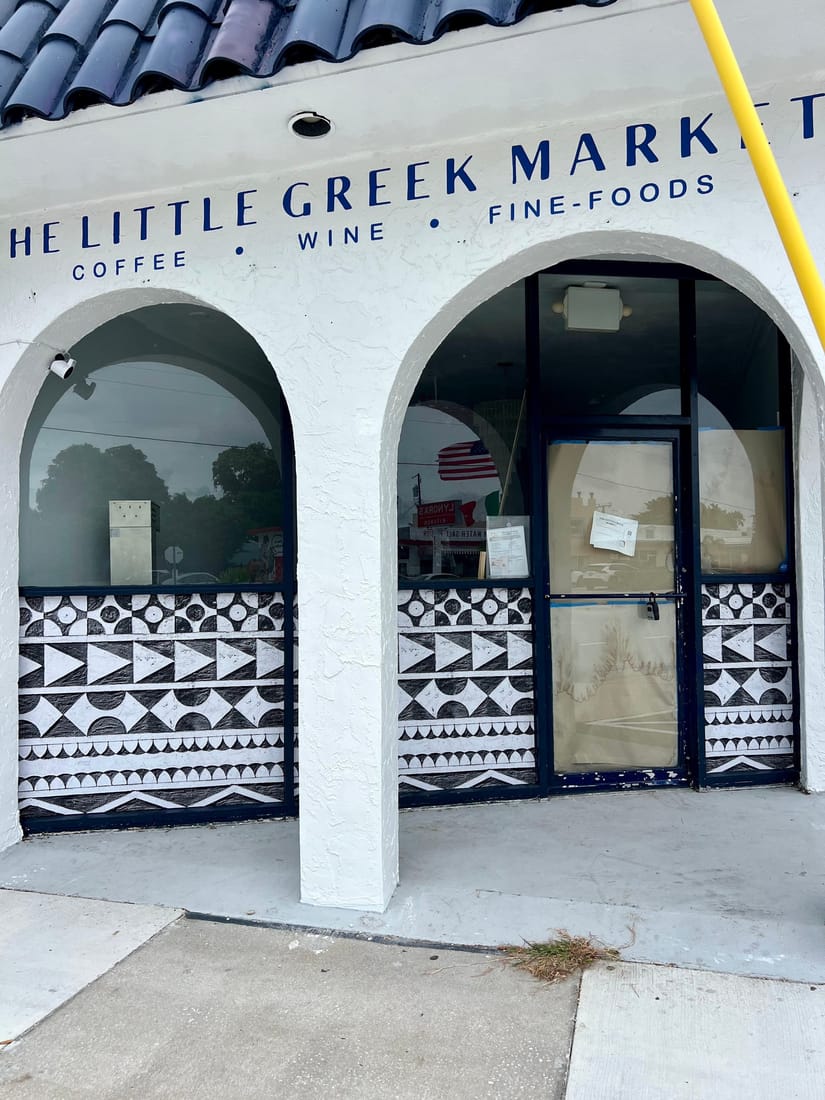 Patterned vinyl on the arched windows of a white stucco shop