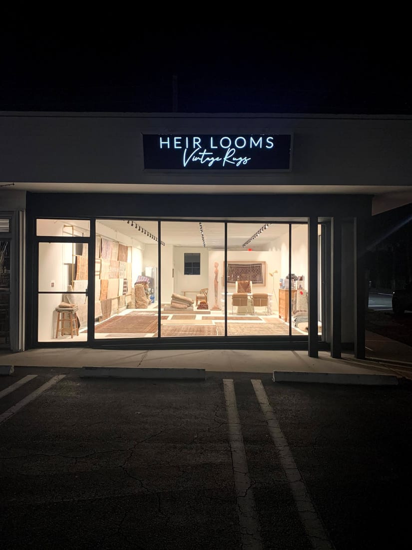 An illuminated sign over a rug gallery at night