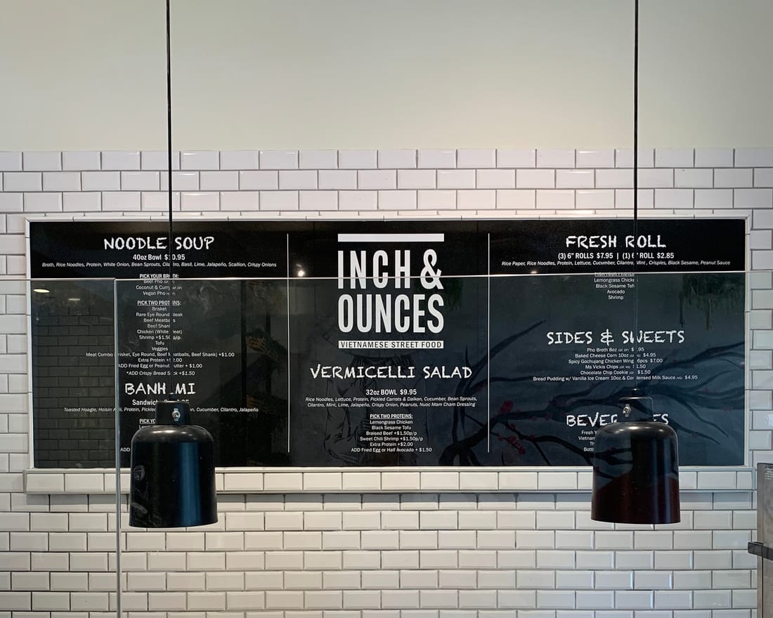 Menu boards mounted on a white tile wall behind a counter