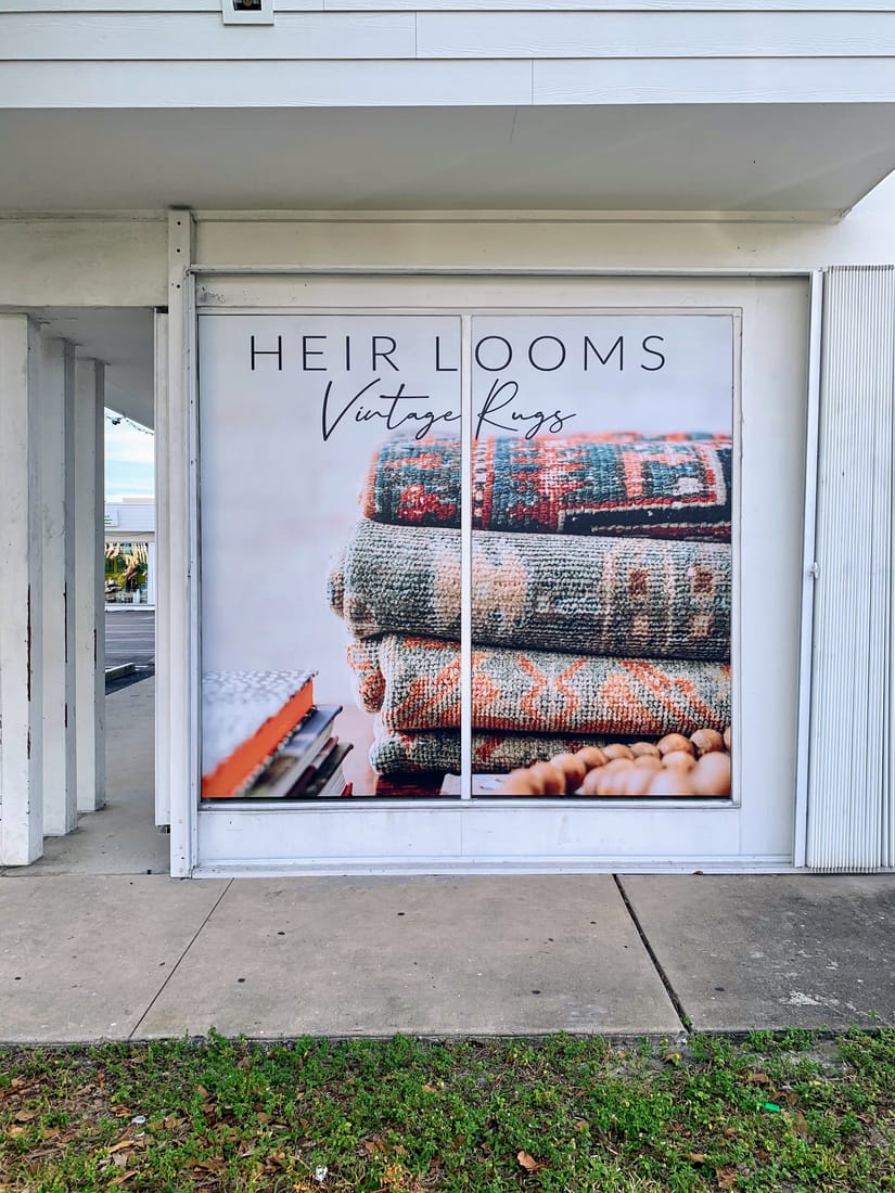 A full-height window graphic of stacked vintage rugs